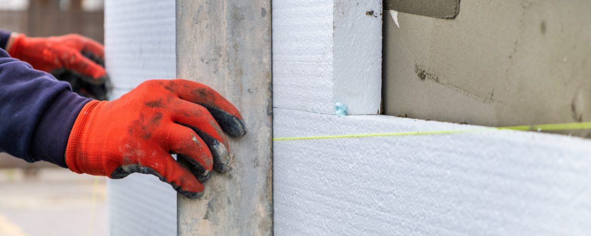 Construction worker installing styrofoam insulation sheets on ho