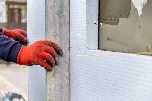 Construction worker installing styrofoam insulation sheets on ho