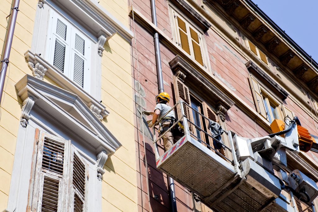 obreros realizando rehabilitación de la fachada de un edificio