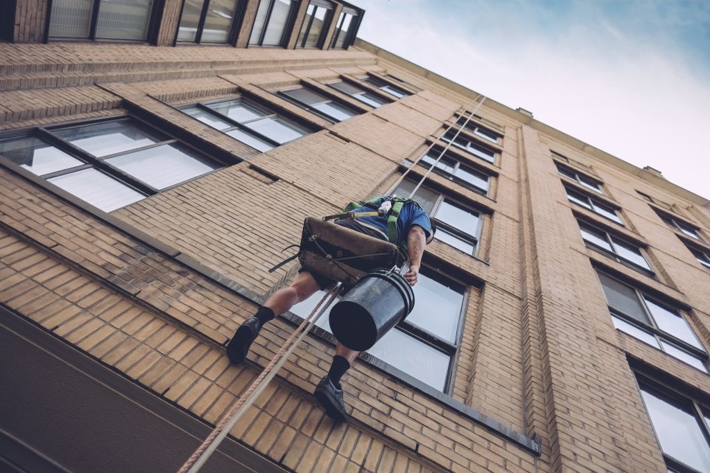 vista de ángulo bajo del lavador de ventanas en el edificio