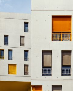 Vertical shot of white buildings with colorful curtains in the windows